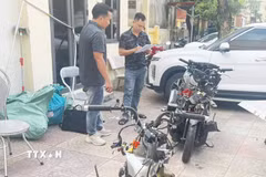 Lực lượng chức năng đang khám nghiệm xe môtô trong vụ tai nạn. (Ảnh: Mạnh Tú/TTXVN