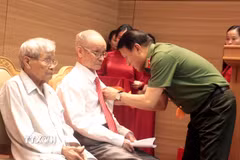 Đại tướng Lương Tam Quang, Ủy viên Bộ Chính trị, Bộ trưởng Bộ Công an trao tặng Huy hiệu 80 năm tuổi Đảng cho các đảng viên. (Ảnh: Đinh Văn Nhiều/TTXVN)