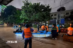 Lực lượng chức năng dùng thuyền di dời các hộ dân về nơi an toàn. (Ảnh: Tiến Vĩnh/TTXVN)