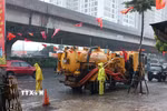Công nhân ứng trực tiêu thoát nước trong mưa lớn tại đường Nguyễn Xiển. (Ảnh: Nguyễn Thắng/TTXVN)