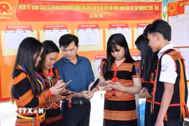 Đồng bào Xơ Đăng (xã Trà Linh, thành phố Đà Nẵng) theo dõi trên điện thoại các video clip, inforgraphic hướng dẫn cách thức đi bỏ phiếu. (Ảnh: Trần Tĩnh/TTXVN)