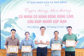 Lãnh đạo xã Phú Riềng khen thưởng cho cá nhân đã kịp thời cứu người do lũ. (Ảnh: TTXVN phát)