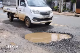 Một xe tải lưu thông qua vị trí mặt đường Nguyễn Huệ bị lún sâu, bong bật lớp nhựa và đọng nước, cho thấy mức độ xuống cấp của tuyến đường. (Ảnh: Đậu Tất Thành/TTXVN.)