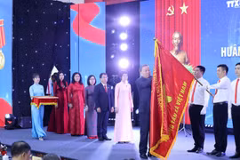 Tổng Bí thư Tô Lâm gắn Huân chương Hồ Chí Minh lên lá cờ truyền thống Thông tấn xã Việt Nam. (Ảnh: Lâm Khánh/TTXVN)