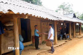 Cán bộ xã Phiêng Pằn (bên phải) tuyên truyền về chủ trương sắp xếp, tổ chức lại thôn, bản đến ông Thào A Mua, dân tộc Mông ở bản Kéo Lồm, sau sắp xếp sẽ thuộc bản Kết Hay. (Ảnh: Quang Quyết/TTXVN)