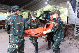 Lực lượng tìm kiếm, quy tập hài cốt liệt sỹ của Bộ Tư lệnh Thành phố Hồ Chí Minh cẩn trọng đưa hài cốt các anh hùng liệt sỹ khỏi hố đào về nơi thực hiện các quy trình tiếp theo.(Ảnh: Xuân Khu/TTXVN)