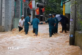 Lực lượng dân quân phường Phước Tân, thành phố Đồng Nai cố băng qua dòng nước chảy xiết để hỗ trợ người dân. (Ảnh minh họa: Lê Xuân/TTXVN)