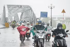 Người dân đi lại trong mưa lớn ở phía Nam cầu Trường Tiền, trung tâm thành phố Huế. (Ảnh: Nguyên Lý/TTXVN)