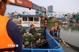 Công nhân Công ty Trách nhiệm hữu hạn Một thành viên Dịch vụ công ích Quận 8 vớt rác trên kênh Đôi, đoạn qua phường Phú Định. (Ảnh: Hồng Đạt/TTXVN)