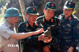 Thượng tướng Nguyễn Văn Gấu, Thứ trưởng Bộ Quốc phòng tỉ mỉ xem những vật dụng còn sót lại tại điểm cao 685. (Ảnh: Đức Thọ/TTXVN)