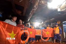 Cán bộ, chiến sỹ Bộ Tư lệnh Vùng Cảnh sát biển 2 trao cờ Tổ quốc và quà động viên ngư dân yên tâm vươn khơi, bám biển, chấp hành đúng các quy định trong khai thác thủy sản. (Ảnh: Xuân Quý/TTXVN)