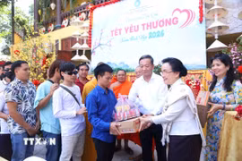 Phu nhân Tổng Bí thư, Chủ tịch nước Lào Naly Sisoulith trao phần quà yêu thương đầu tiên cho người khuyết tật. (Ảnh: Xuân Tú/TTXVN)