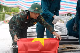 Lực lượng chức năng thực hiện di quách để làm nhiệm vụ lấy mẫu xét nghiệm. (Ảnh: Lê Xuân/TTXVN) 
