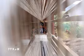 Người phụ nữ Lự ngồi bên khung cửi dệt vải, một nét văn hóa đặc sắc được truyền từ thế hệ này sang thế hệ khác. (Ảnh: Quý Trung/TTXVN)