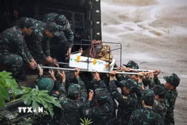 Lực lượng cán bộ chiến sỹ di chuyển đầu nổ quả bom có trọng lượng gần 1000kg lên xe để chuyển đi hủy nổ. (Ảnh: Trọng Đạt/TTXVN)