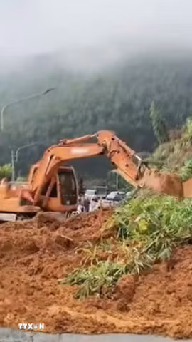 Máy xúc khẩn trương thu dọn đất tràn xuống mặt đường tỉnh 755B, đoạn qua xã Phước Sơn, thành phố Đồng Nai, sau mưa lớn kéo dài. (Ảnh: TTXVN phát)