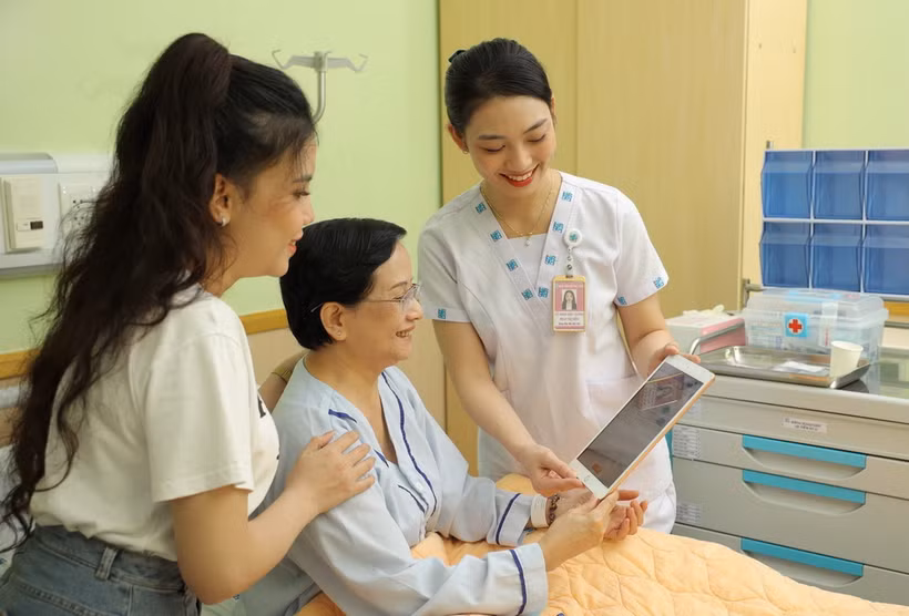  Nhân viên y tế Bệnh viện Đại học Y dược Thành phố Hồ Chí Minh sử dụng máy tính bảng cập nhật và chia sẻ thông tin với người bệnh. (Ảnh: TTXVN phát)