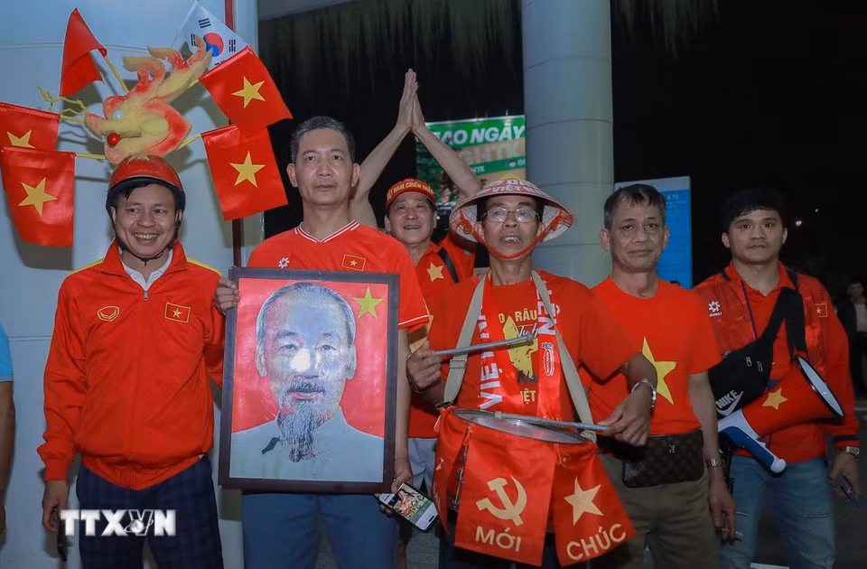 Người hâm mộ mang ảnh Bác Hồ chào đón đội tuyển. (Ảnh: Phan Phương/TTXVN)