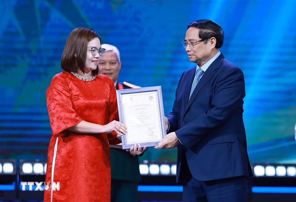 Thủ tướng Phạm Minh Chính trao Giải A cho đại diện nhóm tác giả với tác phẩm "Làm gì với trụ sở dôi dư?" phát sóng trên VOV giao thông, Đài Tiếng nói Việt Nam. (Ảnh: Dương Giang/TTXVN)