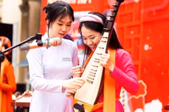 Nữ sinh Trường Trung học phổ thông Trần Phú (Hà Nội) thích thú khi lần đầu tiên được chạm tay vào đàn tì bà. (Ảnh: Vietnam+)