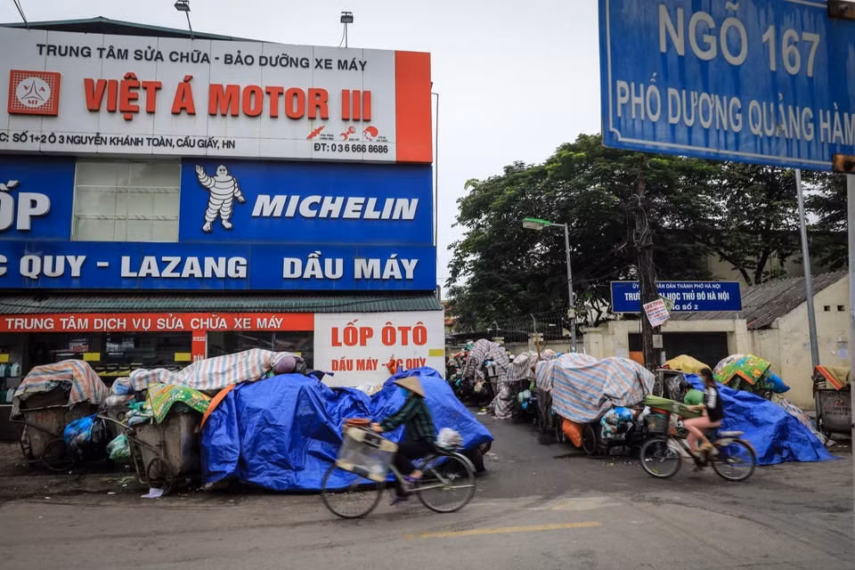 Đầu ngõ 167 Dương Quảng Hàm (Quận Cầu Giấy, Hà Nội) hàng dài xe rác ứ đọng, phủ bạt nằm chờ được di dời đến điểm tập kết. (Ảnh: Thành Đạt/TTXVN)