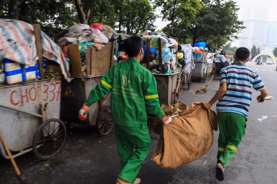 Công nhân môi trường vệ sinh, dọn rác thải vương vãi ra đường tại đường Khúc Thừa Dụ (quận Cầu Giấy). (Ảnh: Thành Đạt/TTXVN)