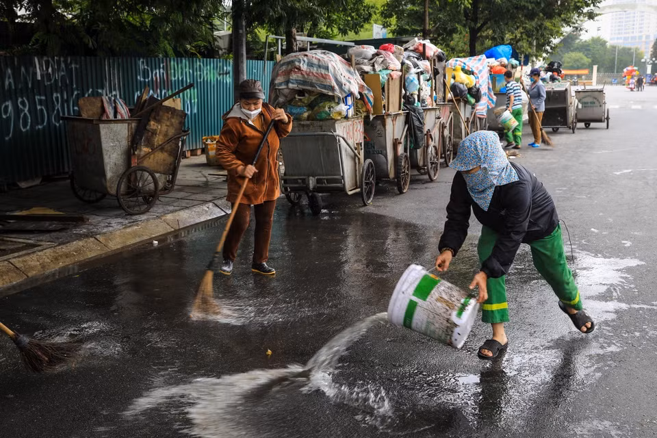 Công nhân môi trường vệ sinh, dọn rác thải vương vãi ra đường tại đường Khúc Thừa Dụ (quận Cầu Giấy). (Ảnh: Thành Đạt/TTXVN)