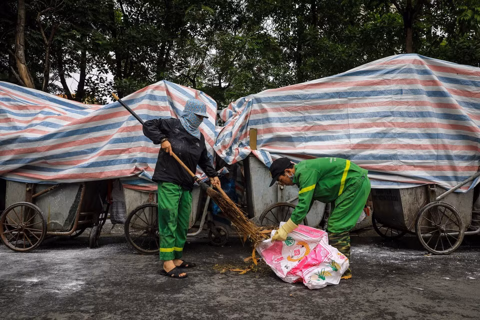 Công nhân môi trường vệ sinh, dọn rác thải vương vãi ra đường tại đường Khúc Thừa Dụ (quận Cầu Giấy). (Ảnh: Thành Đạt/TTXVN)