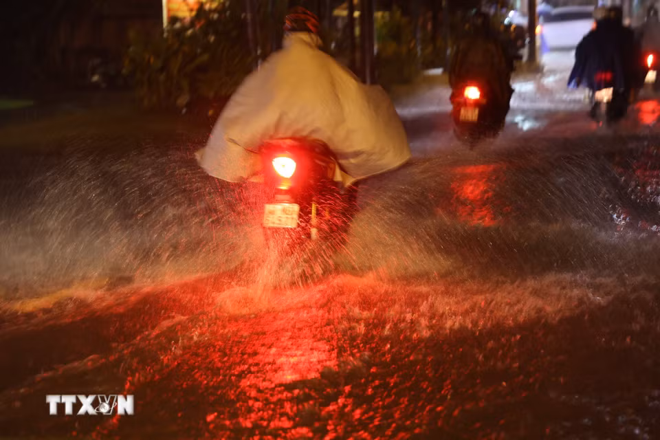 Người dân Thành phố Hồ Chí Minh di chuyển trong mưa và ngập tối 30/9 trên đường Bình Quới, phường Bình Quới. (Ảnh: Hồng Đạt/TTXVN)