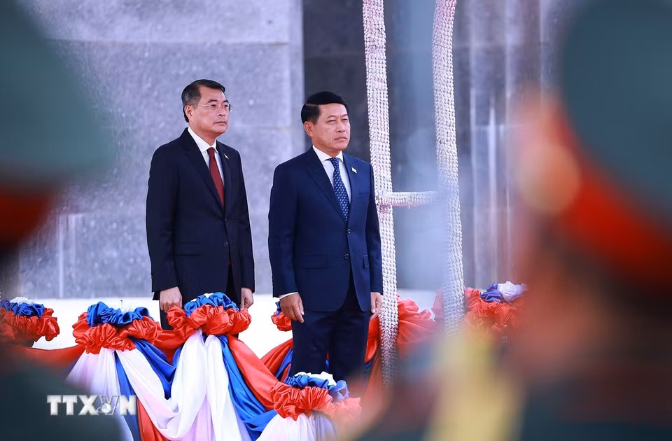 Thủ tướng Lê Minh Hưng và Thủ tướng Saleumxay Kommasith nghe Quân nhạc cử Quốc thiều hai nước. (Ảnh: Dương Giang/TTXVN)