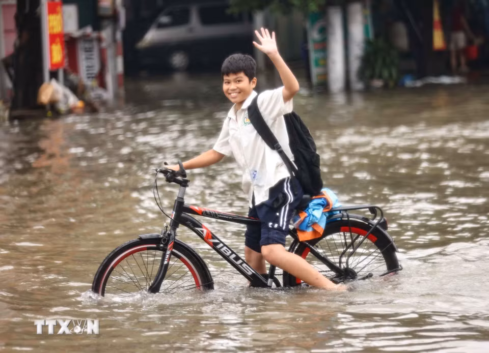 Học sinh trở về nhà phải đi vào đường Tây Mỗ đang bị ngập. (Ảnh: Thanh Tùng/TTXVN)