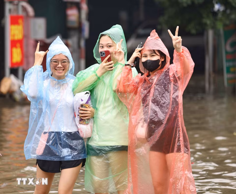 Dù phải lội nước để về nhà song người dân vẫn lạc quan, mong nước rút sớm. (Ảnh: Thanh Tùng/TTXVN)