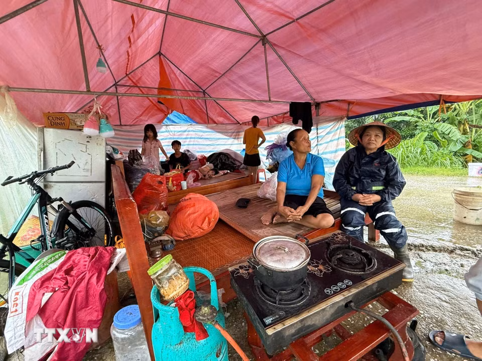Mưa, rét, khó khăn đủ bề nhưng gia đình bà Vũ Thị Chừ, 72 tuổi, xã Kim Tân vẫn động viên nhau cùng cố gắng, đợi nước rút sẽ về dọn dẹp nhà cửa. (Ảnh: Hoa Mai/TTXVN)