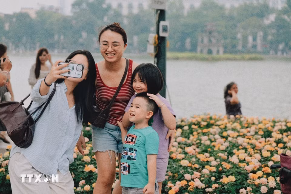 Người dân hào hứng chụp ảnh lưu niệm bên những vườn hoa rực rỡ sắc màu tại khu vực hồ Hoàn Kiếm. (Ảnh: Phạm Tuấn Anh/TTXVN)