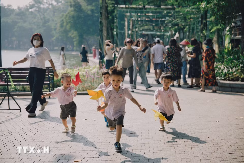 Các em nhỏ vui đùa với chong chóng. (Ảnh: Phạm Tuấn Anh/TTXVN)