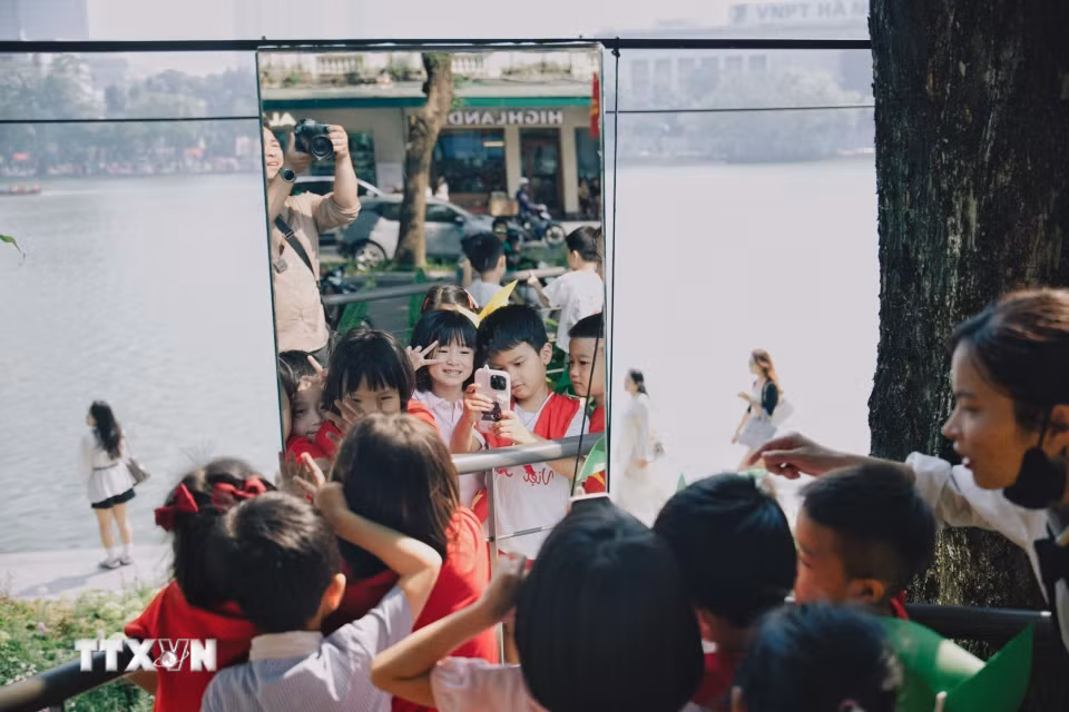 Các em nhỏ hào hứng chụp ảnh lưu niệm qua hệ thống gương nghệ thuật tại không gian “Dải lụa ký ức” bên hồ Hoàn Kiếm trong dịp kỷ niệm 72 năm Ngày Giải phóng Thủ đô. (Ảnh: Phạm Tuấn Anh/TTXVN)