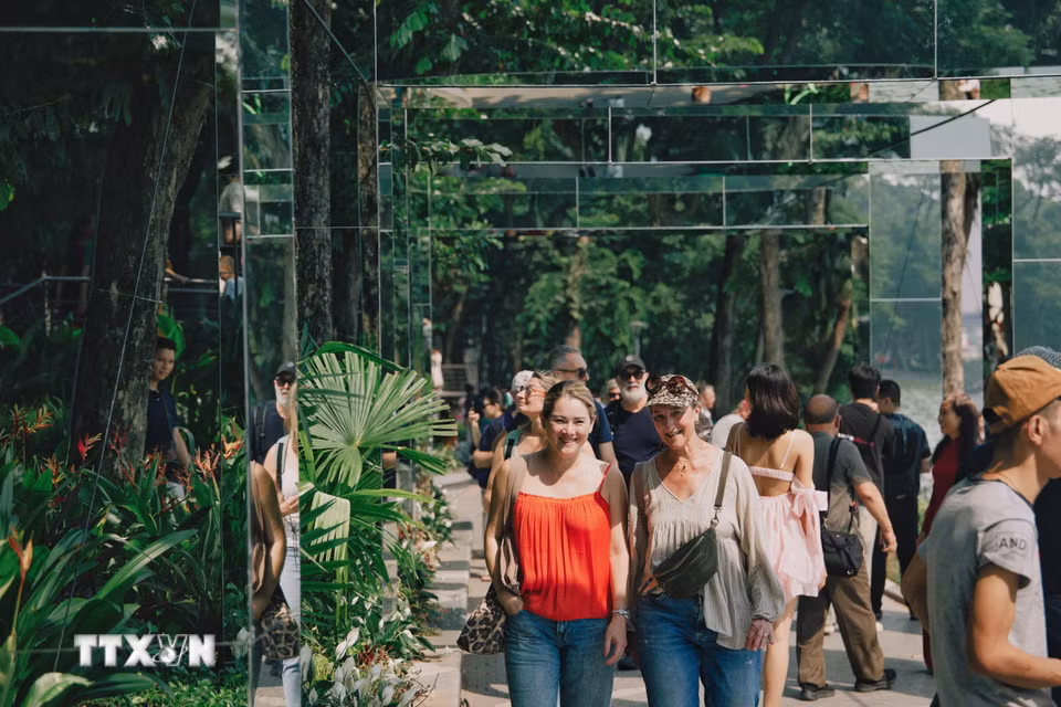 Du khách quốc tế tham quan, dạo bước giữa hệ thống khung gương nghệ thuật tại không gian “Dải lụa ký ức” bên hồ Hoàn Kiếm. (Ảnh: Phạm Tuấn Anh/TTXVN)
