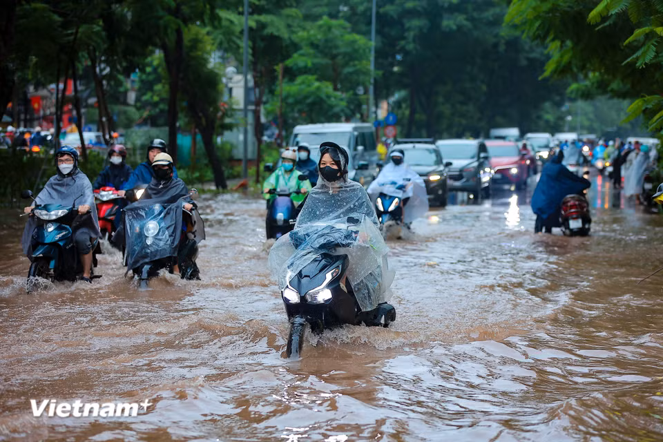 Người dân di chuyển qua đoạn 'phố biến thành sông' đầu giờ sáng nay. (Ảnh: Hoài Nam/Vietnam+)