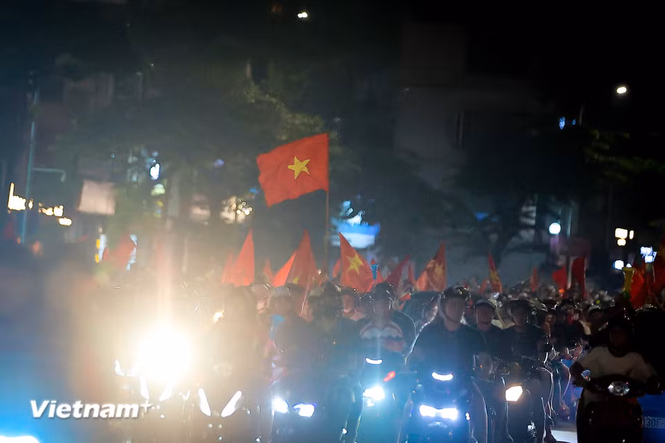 Càng về khuya, không khí ăn mừng càng trở nên thăng hoa, những lá đại kỳ tung bay kiêu hãnh trong ánh sáng rực rỡ. (Ảnh: Hoài Nam/Vietnam+)