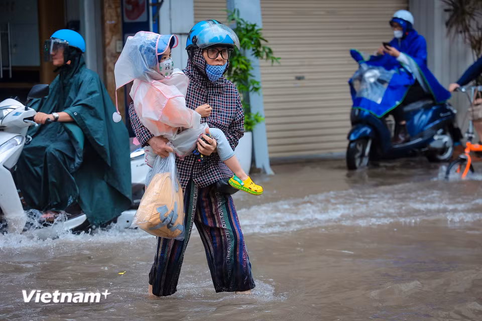 Do mưa lớn kéo dài khiến đường phố vẫn ngập kèm theo mưa khiến đầu giờ sáng của nhiều gia đình trở nên 'vất vả' hơn. (Ảnh: Hoài Nam/Vietnam+)