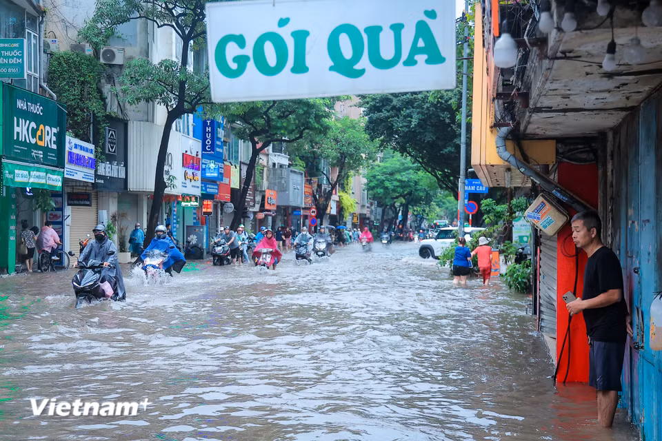Mưa lớn kéo dài từ đêm qua khiến một số tuyến đường của Hà Nội ngập sâu, người dân chật vật đưa con đi học đi làm. (Ảnh: Hoài Nam/Vietnam+)