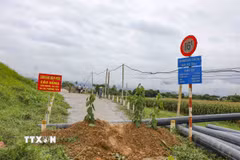 Lực lượng chức năng cắm biển cảnh báo, ngăn người và phương tiện qua cầu C9 sau khi phát hiện mố cầu bị xói lở nghiêm trọng. (Ảnh: Xuân Tư/TTXVN)