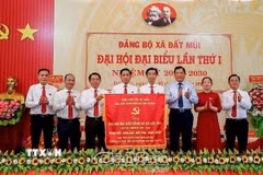 Thay mặt Tỉnh ủy, Phó Chủ tịch UBND tỉnh Cà Mau Lâm Văn Bi (thứ 3 từ phải sang), trao tặng Đại hội bức trướng mang dòng chữ "Đoàn kết-Dân chủ-Đột phá-Phát triển" khai thác lợi thế, phát triển Đất Mũi thành đô thị sinh thái hiện đại ở cực Nam của Tổ quốc. (Ảnh TTXVN phát)