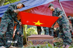 Chiến sỹ phủ cờ Tổ quốc lên tiểu sành đựng hài cốt liệt sỹ. (Ảnh: Xuân Tư/TTXVN)