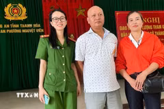 Tại Công an phường Nguyệt Viên, anh Đỗ Trung Cương (giữa) trao trả tiền chuyển nhầm cho chị Đặng Thị Kim Liên (bên phải) trú tại xã Phú Xuyên, thành phố Hà Nội. (Ảnh: TTXVN phát)