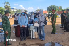 Lực lượng chức năng Việt Nam-Campuchia làm thủ tục bàn giao, tiếp nhận 353 công dân Việt Nam tại Cửa khẩu quốc tế Xa Mát, xã Tân Lập, tỉnh Tây Ninh. (Ảnh: TTXVN phát)