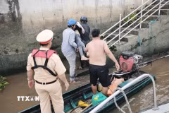 Cán bộ, chiến sỹ Cảnh sát đường thủy số 2 phối hợp đưa nạn nhân từ xuồng máy lên bờ để sơ cứu, chuyển đến cơ sở y tế cấp cứu. (Ảnh: TTXVN phát)