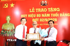 Đoàn công tác trao Huy hiệu 80 năm tuổi Đảng và hoa chúc mừng đảng viên Huỳnh Long Tòa, xã Cầu Ngang. (Ảnh: Thanh Hòa/TTXVN)