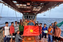 Lực lượng chấp pháp trên biển trao cờ tổ quốc và tuyên truyền IUU cho ngư dân đang đánh bắt trên biển. (Ảnh minh họa: Hoàng Nhị/TTXVN)