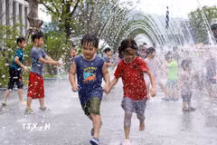 Các em nhỏ chơi đùa bên đài phun nước để tránh nóng tại Seoul, Hàn Quốc. (Ảnh: THX/TTXVN)